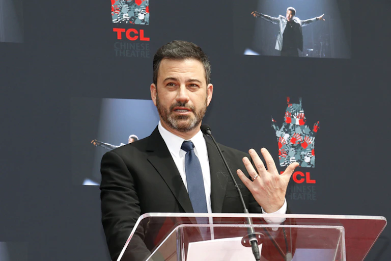 US comedian Jimmy Kimmel gestures with his hand while standing at a podium.