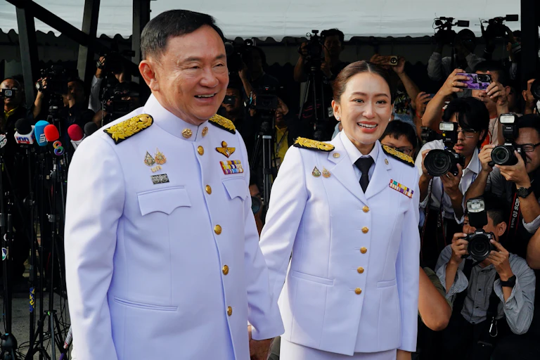 Paetongtarn Shinawatra walks with her father, Thaksin Shinawatra.