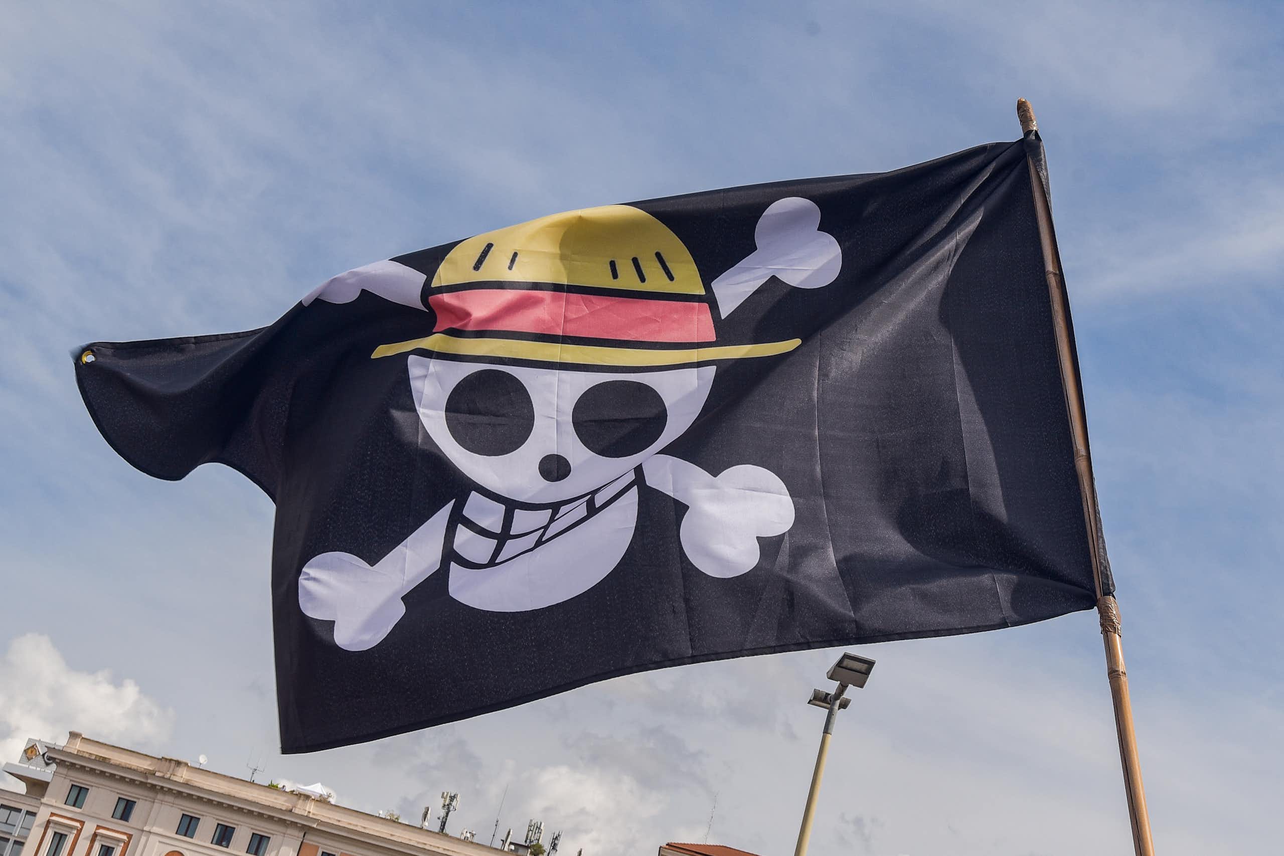 A grinning skull and crossbones is seen on a black flag.