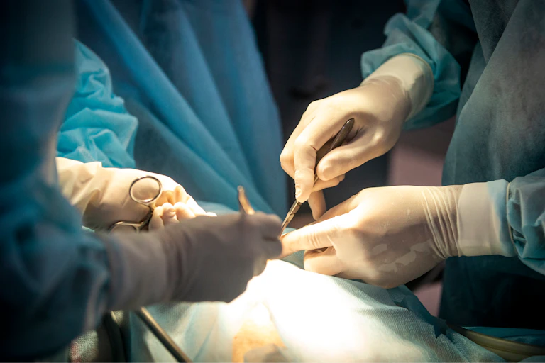 Surgeons operating on a patient. Just their gloved hands are visible.