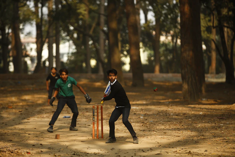 Nepalese people playing cricket on a makeshift pitch.