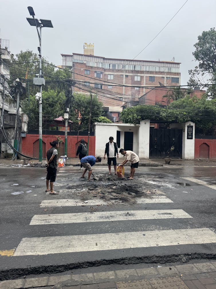 A group of Nepalese people clearing debris from a street in Kathmandu.