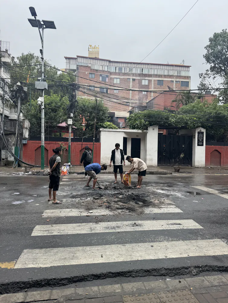 A group of Nepalese people clearing debris from a street in Kathmandu.