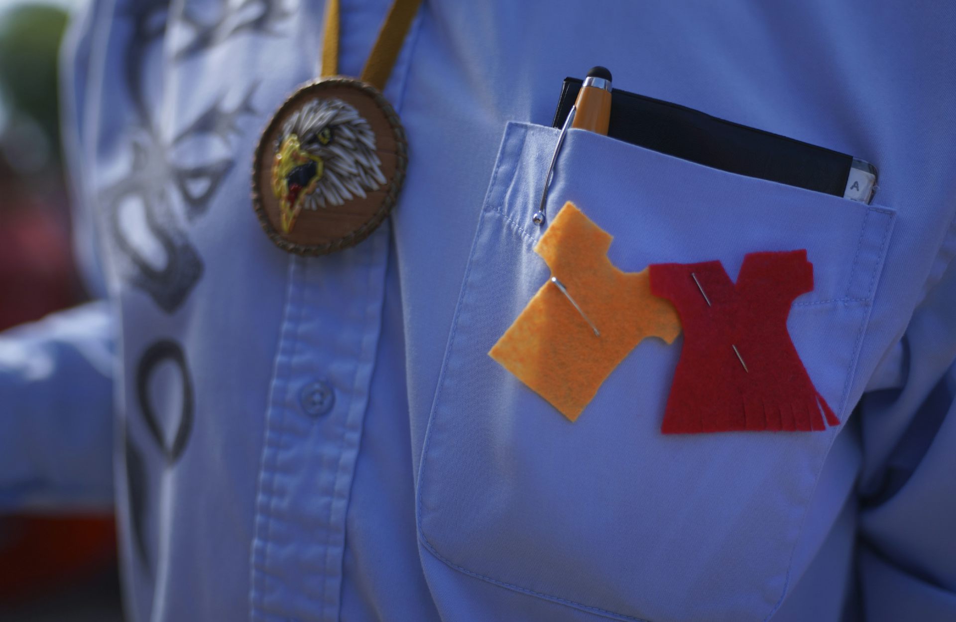 Orange and red shirts seen pinned to a chest pocket, beside an eagle beading.