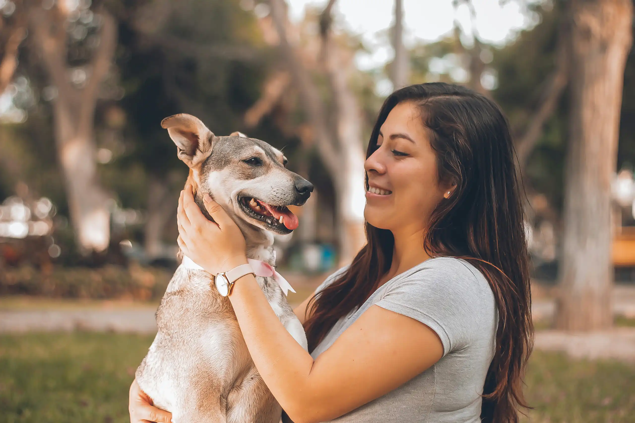 A woman holding a white and grey dog outdoors
