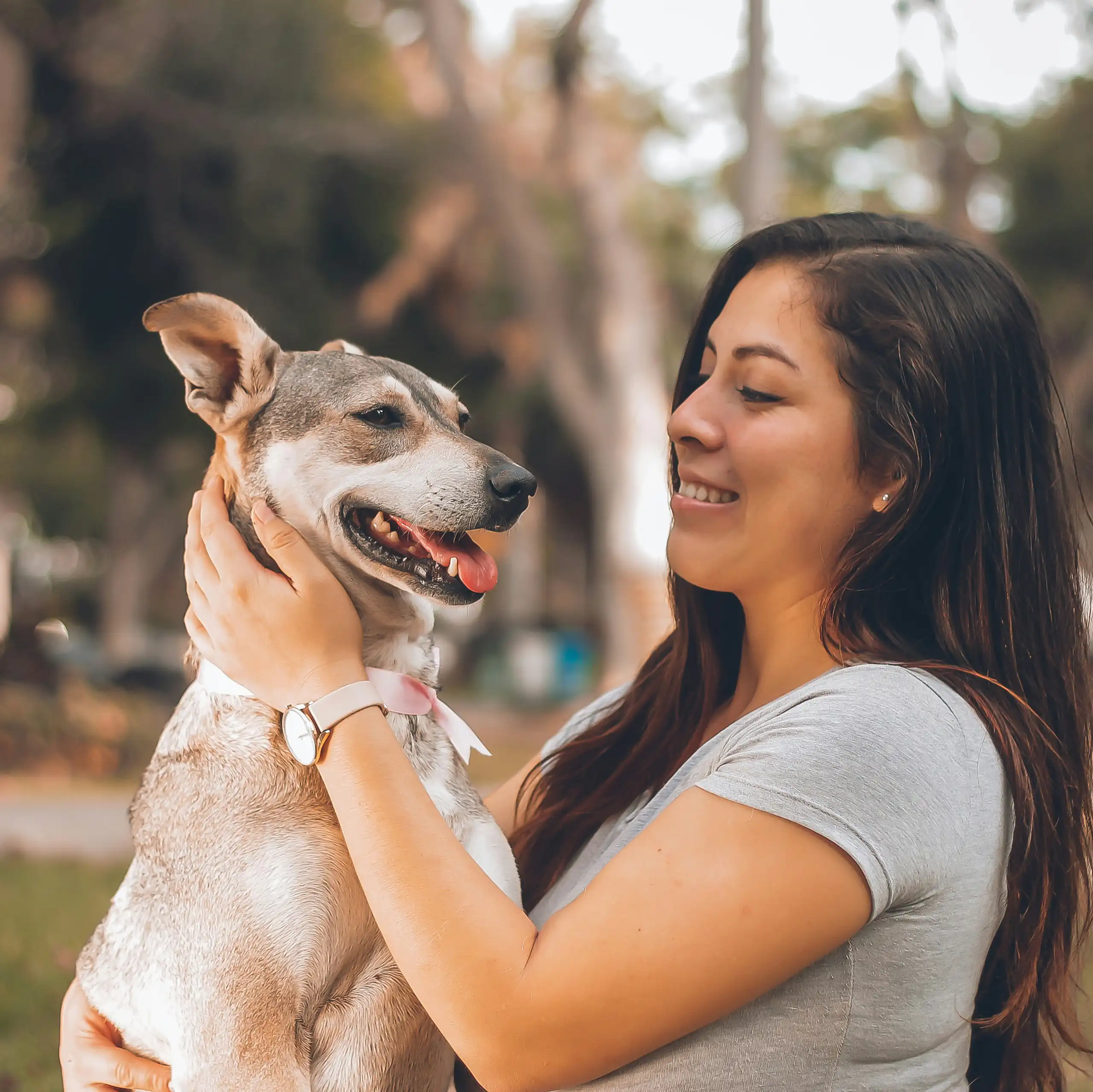 A woman holding a white and grey dog outdoors