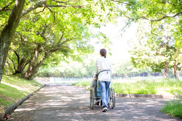 Person in a wheelchair and their carer. Photo taken from behind.
