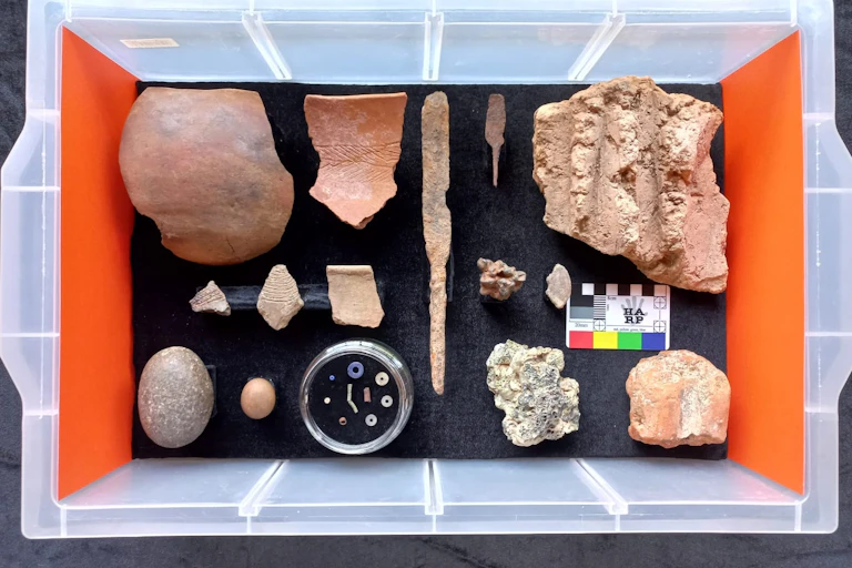 Pottery sherds, stone tools, beads, fragments of iron in a plastic box