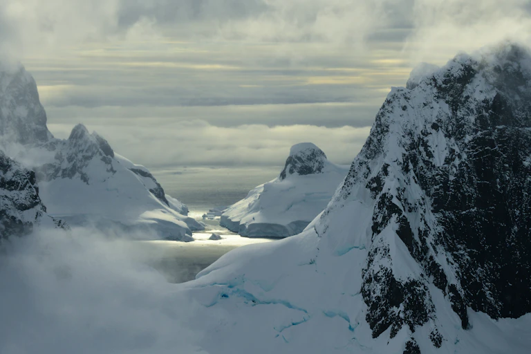 antarctic mountains, landscape photo with sun peeping through cloud.