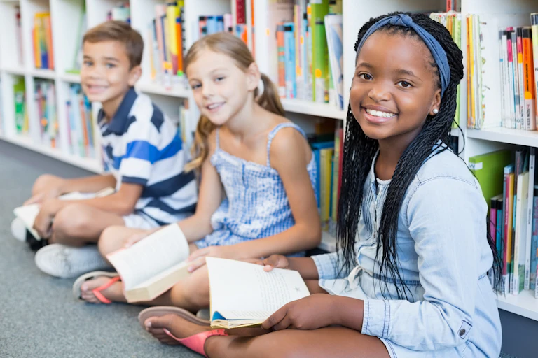 Smiling children with books in library