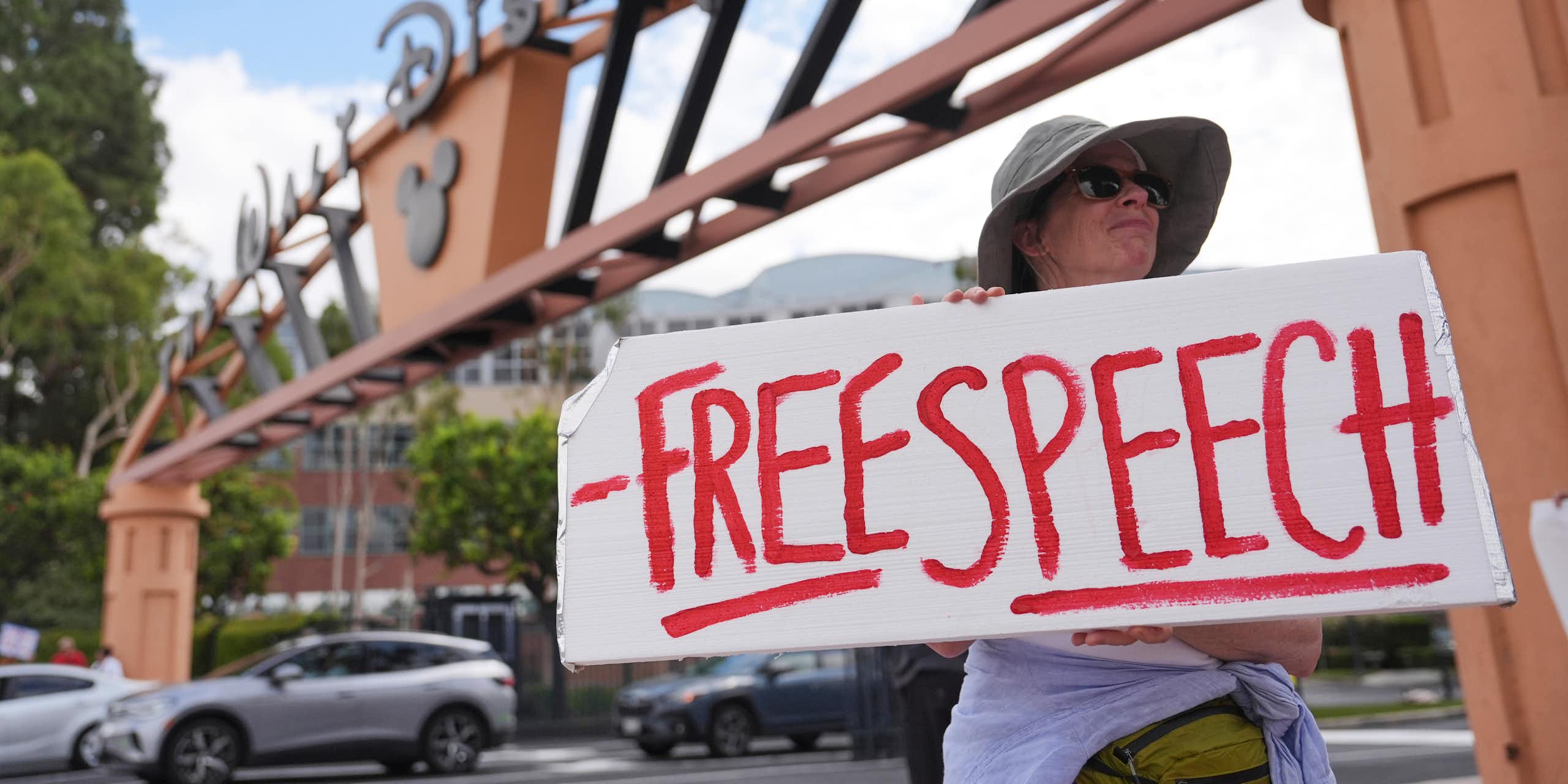 A demonstrator holds a sign that reads Free Speech.