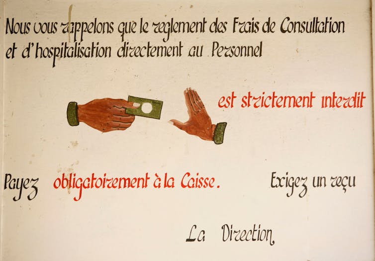 A beige sign with illustrations of one hand holding money reaching out toward another hand signaling 'stop.'
