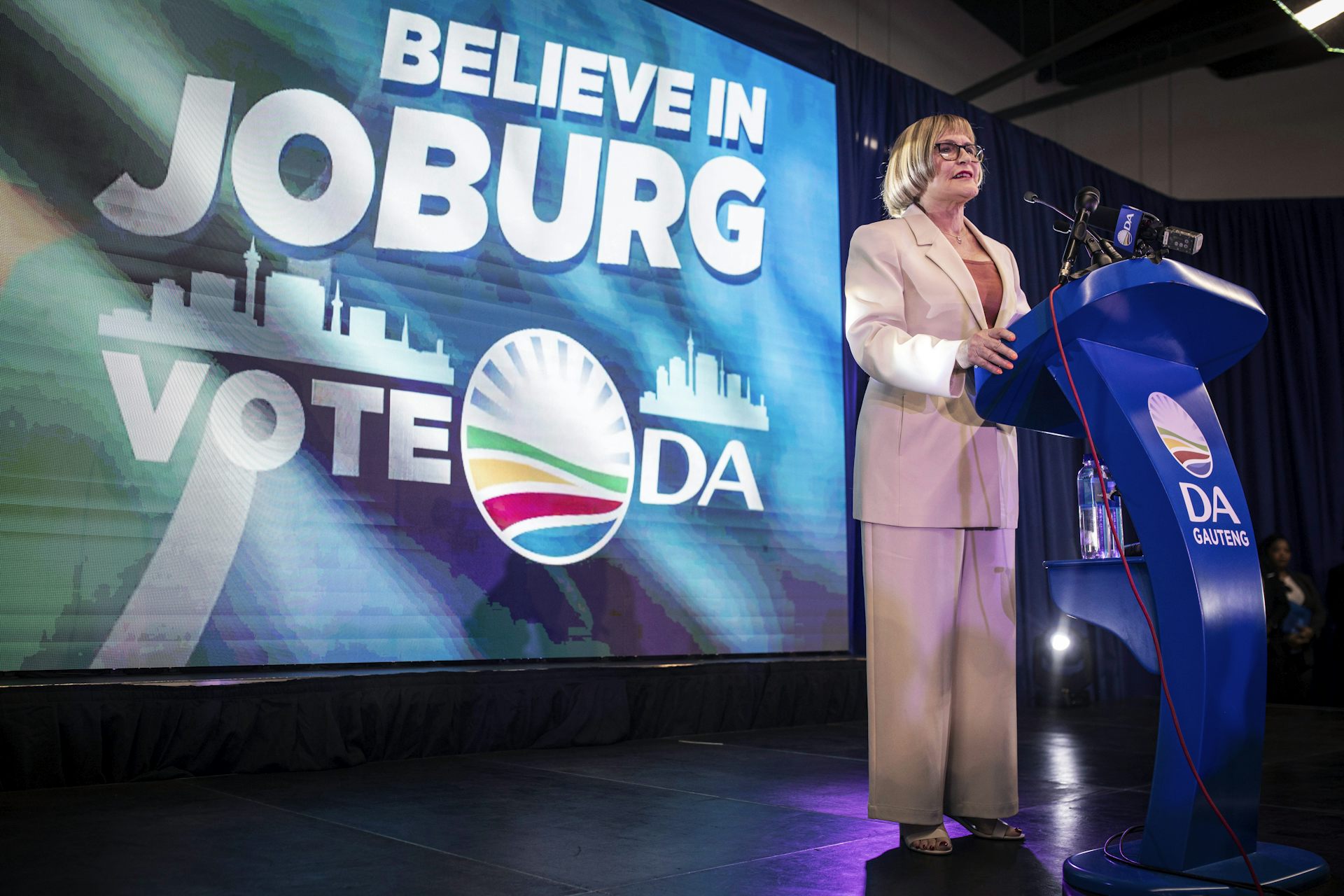 An older woman in a suit at a podium.