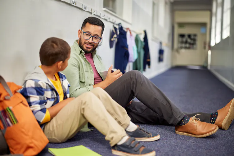 Adult talking to child in school corridor
