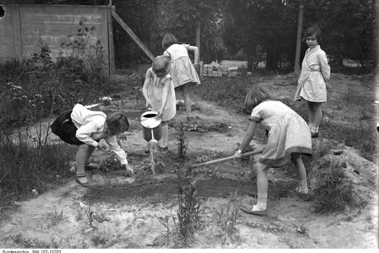 Foto en blanco y negro con niños trabajando con herramientas en un patio.