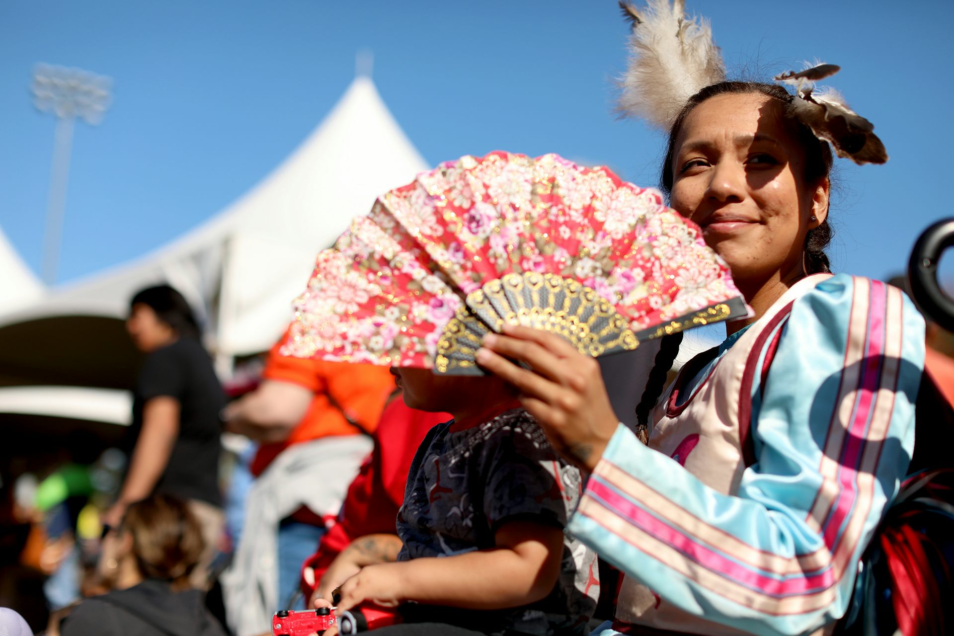 Una mujer vestida con fanáticos autóctonos tradicionales y su hijo mientras asiste al crecimiento.