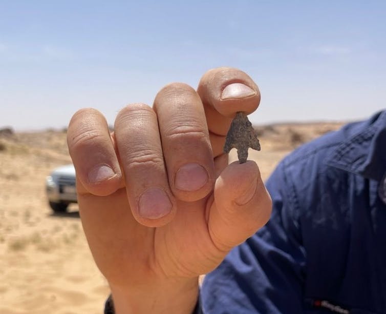 A hand holding a small arrowhead.