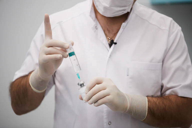 A man in a white lab coat preparing an injection.