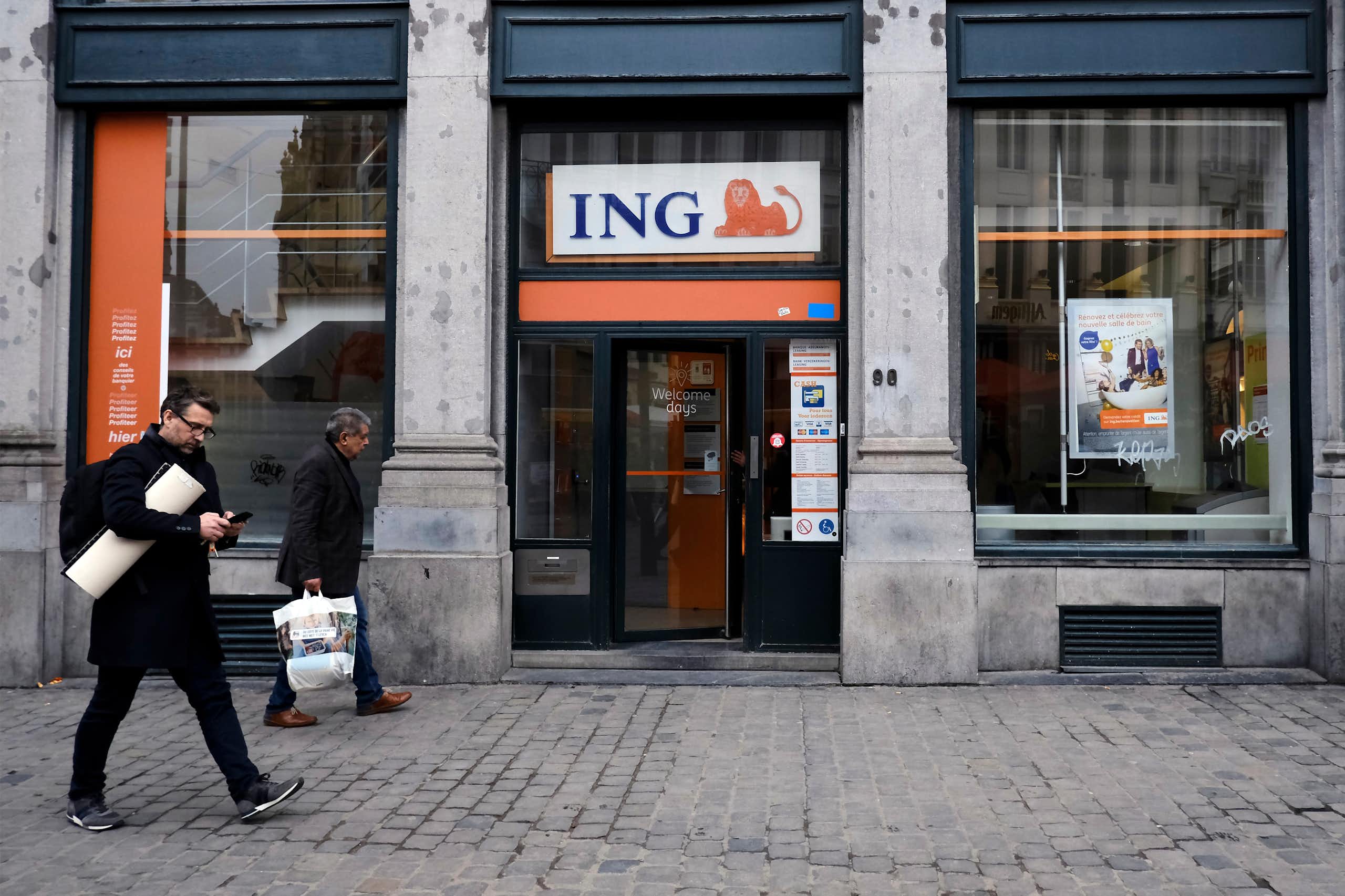 Pedestrians walk outside of ING bank 's branch in Brussels, Belgium.