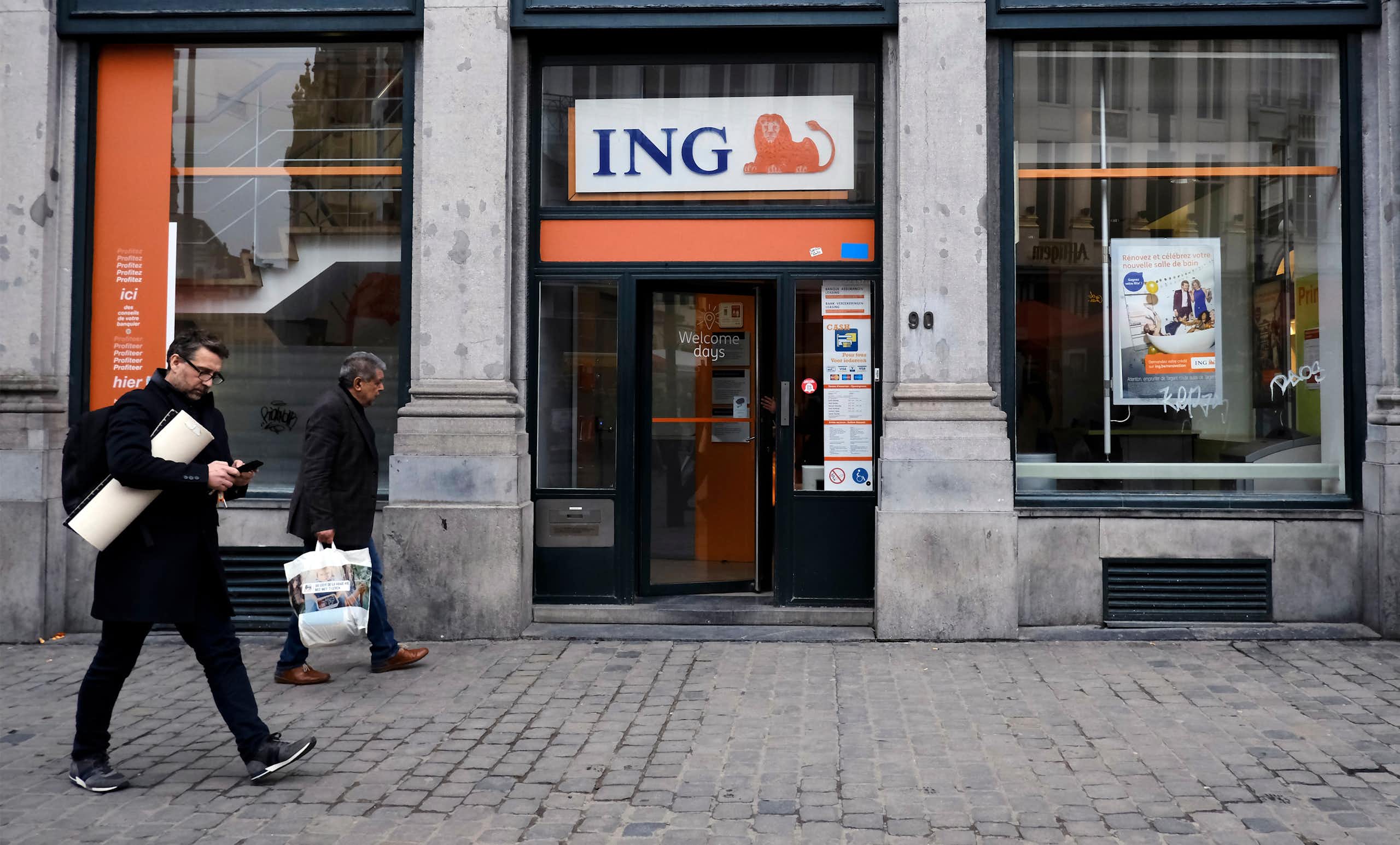 Pedestrians walk outside of ING bank 's branch in Brussels, Belgium.