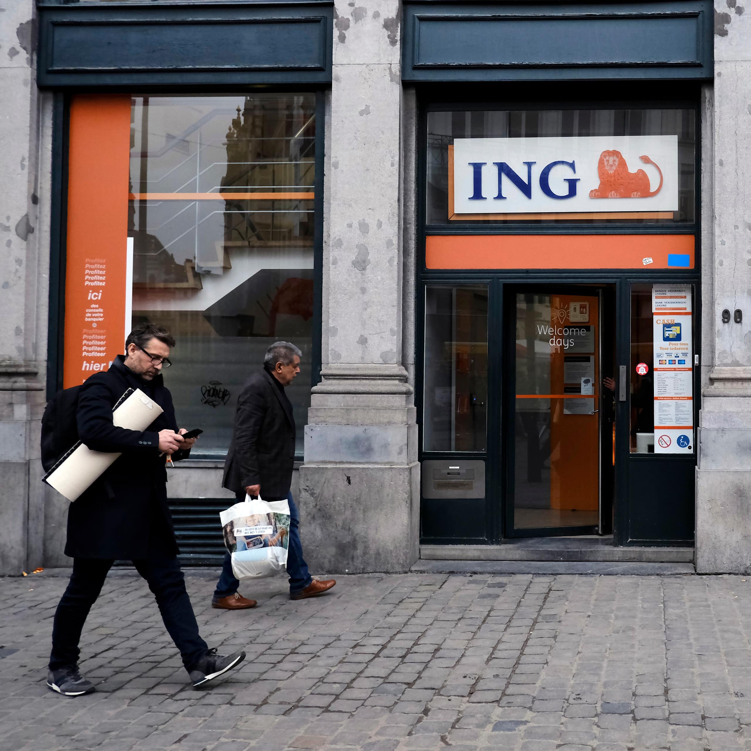 Pedestrians walk outside of ING bank 's branch in Brussels, Belgium.