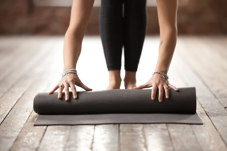 Woman rolling up yoga mat