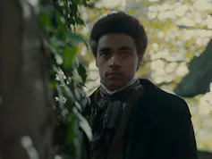 Un hombre de piel negra observa algo fuera de campo.