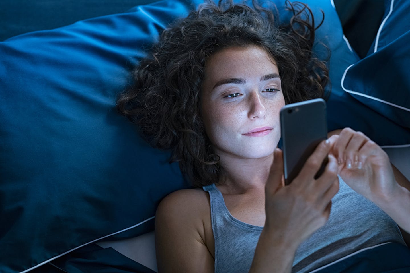Woman looking at her phone in bed.