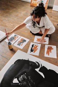 La mujer está sentada en las fotos del piso de madera.