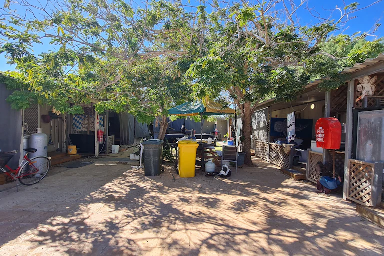 A courtyard with trees and rubbish bins in between two undercover areas