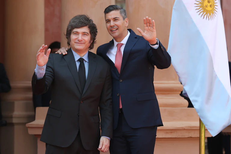 Javier Milei and Santiago Peña wave during a welcome ceremony.