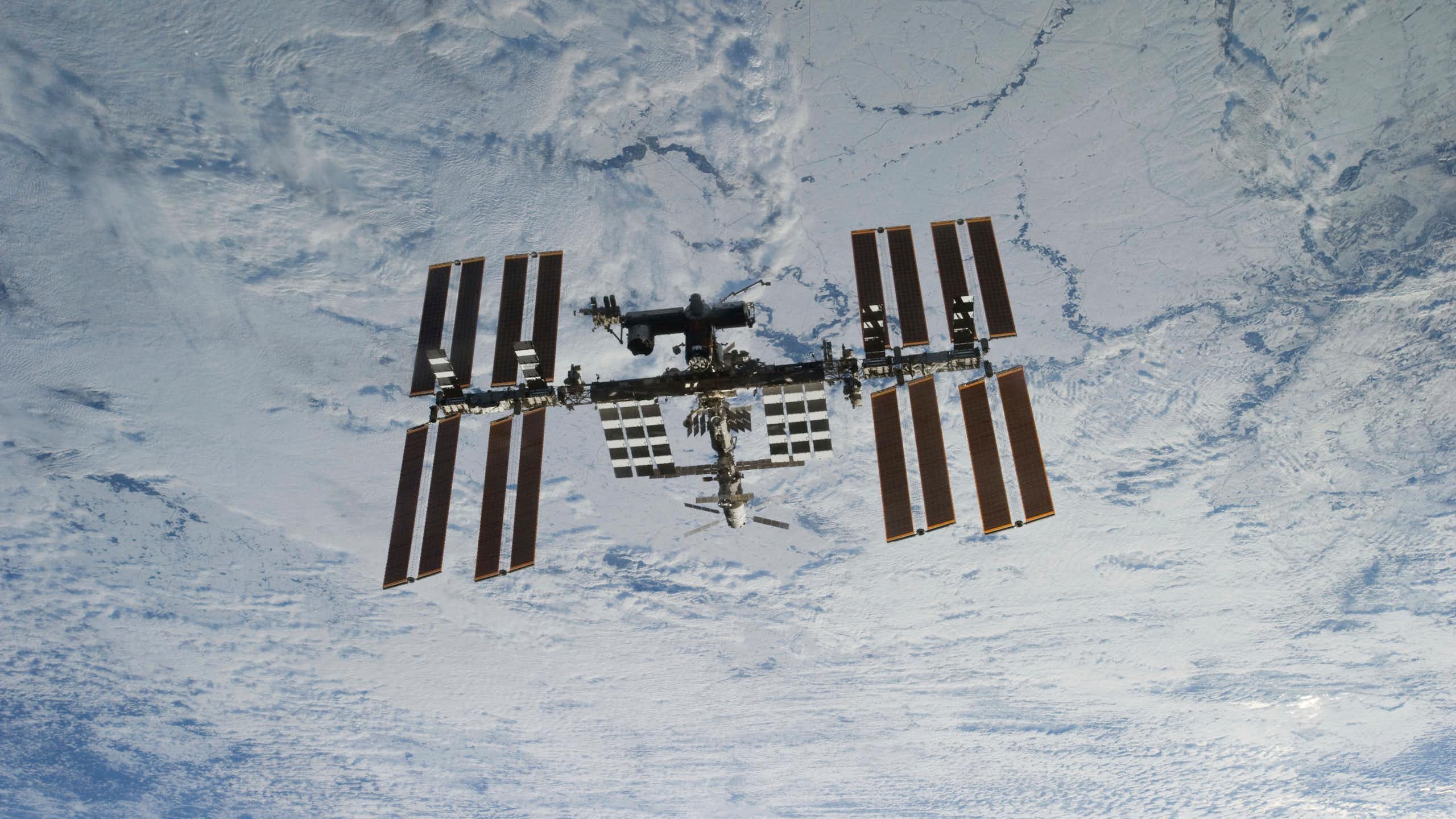 L’ISS flottant dans l’espace sur fond de nuages dans l’atmosphère terrestre.