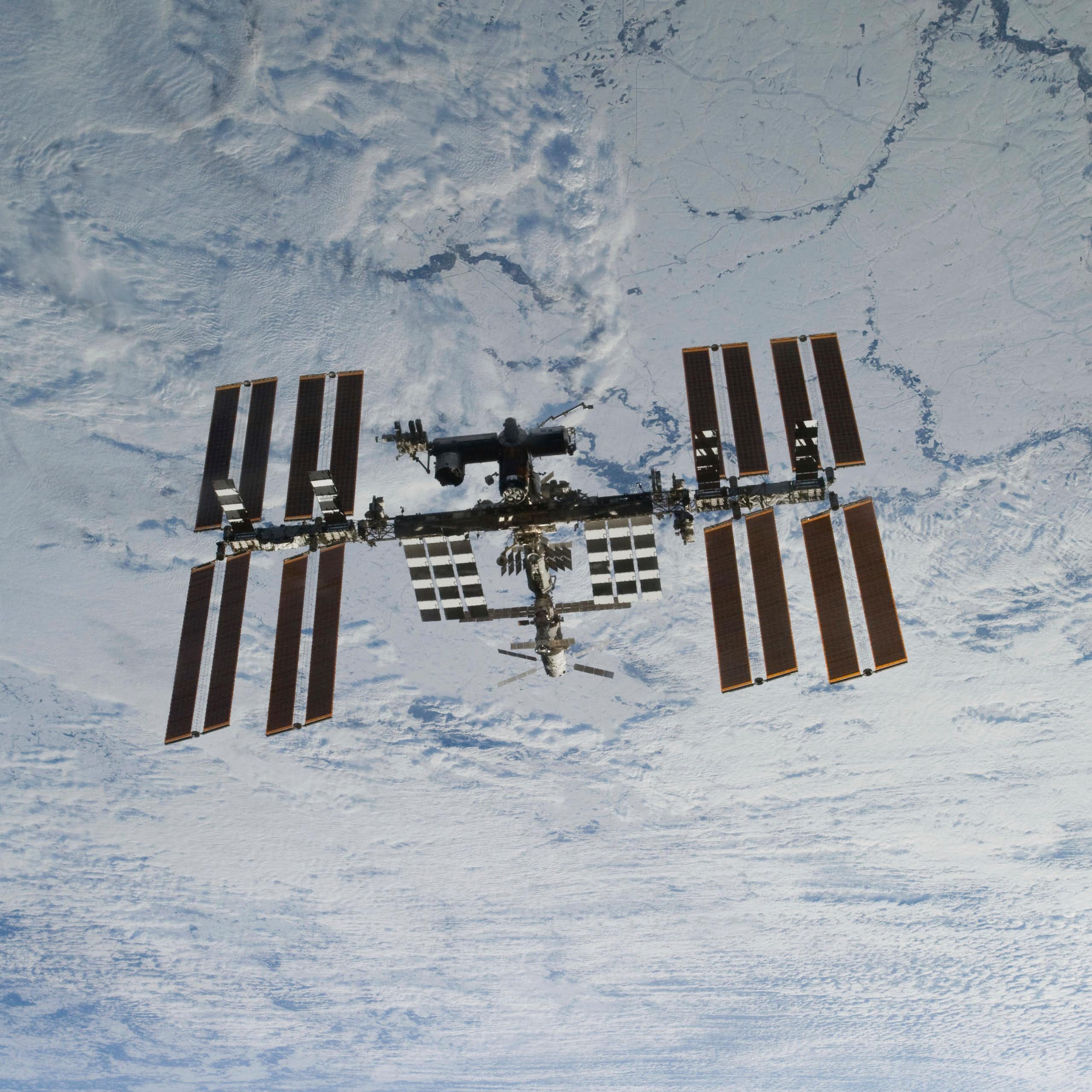 L’ISS flottant dans l’espace sur fond de nuages dans l’atmosphère terrestre.