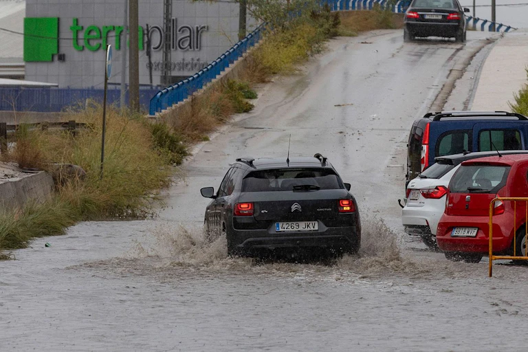 Un coche circula por una carretera inundada