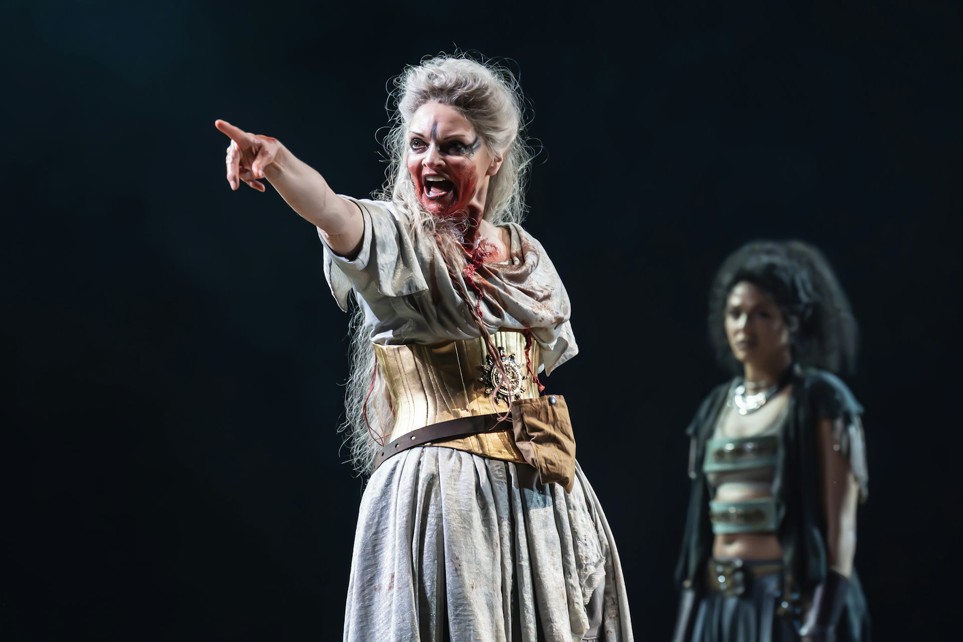A woman on stage pointing and looking evil.