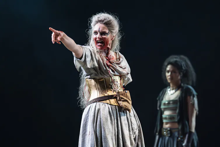 A woman on stage pointing and looking evil.