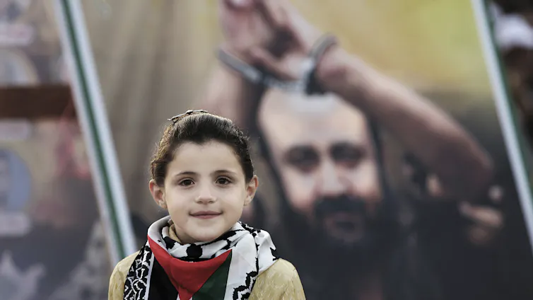 A young Palestinian girl poses in front of a picture of jailed Fatah leader Marwan Barghouti.