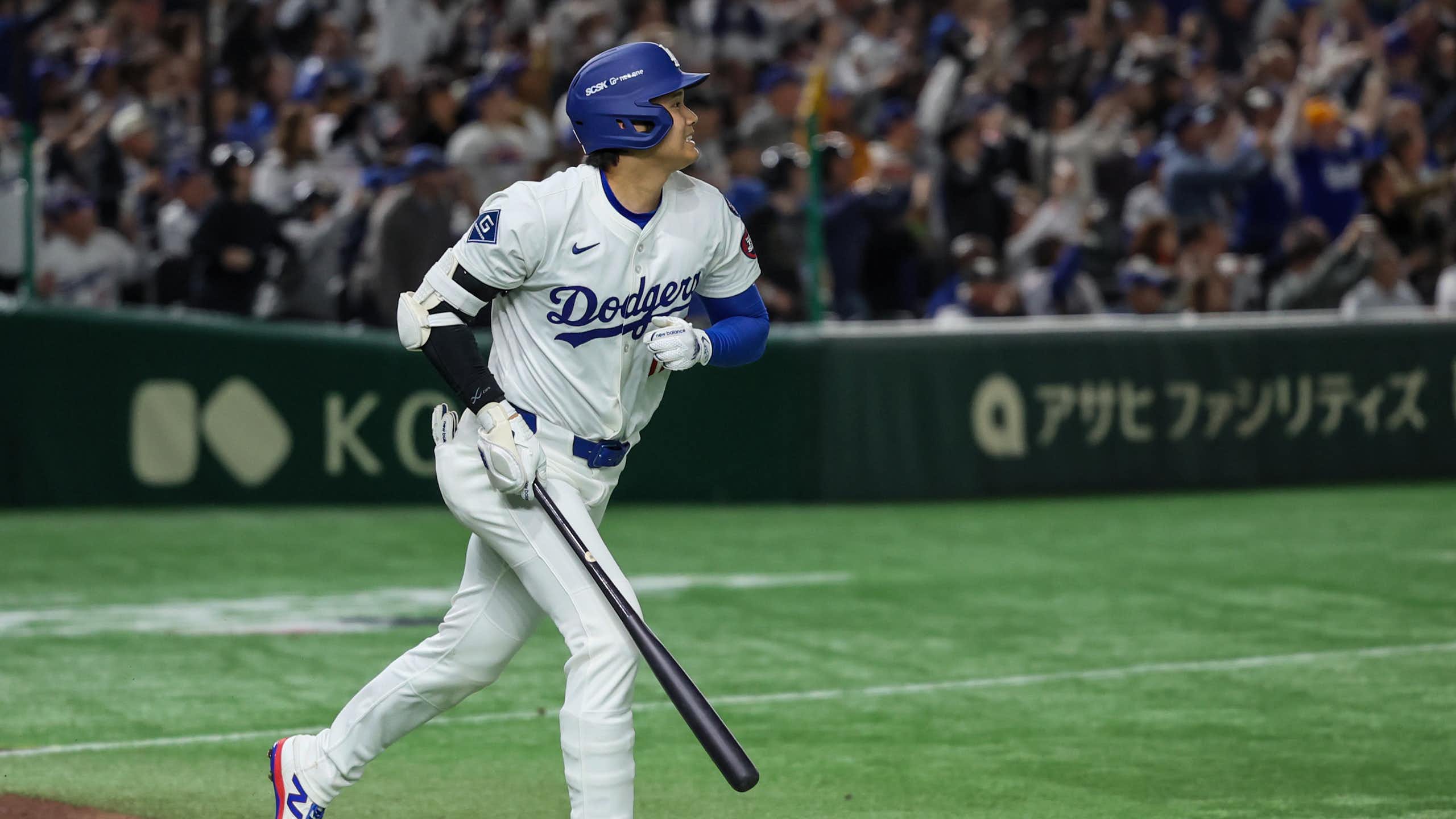 A baseball player is seen breaking into a trot with a broad smile.