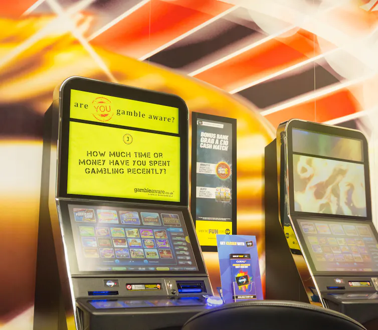 A betting terminal in a shop with a yellow screen reading 'how much time or money have you spent gambling recently?'