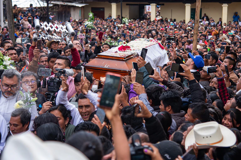 A coffin being carried through a crowd of people in Mexico.