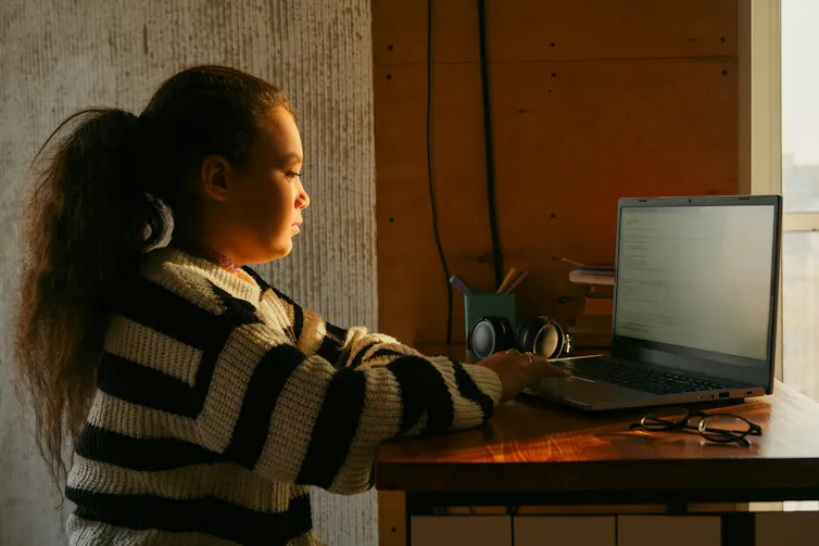 a young girl sits at a computer