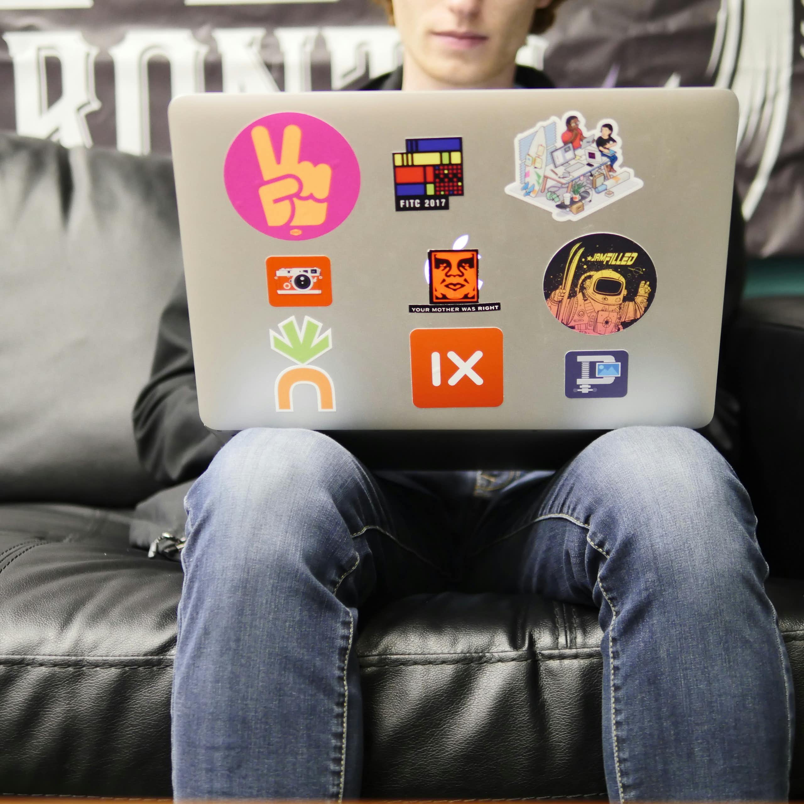 a teen boy using a laptop while sitting on a couch