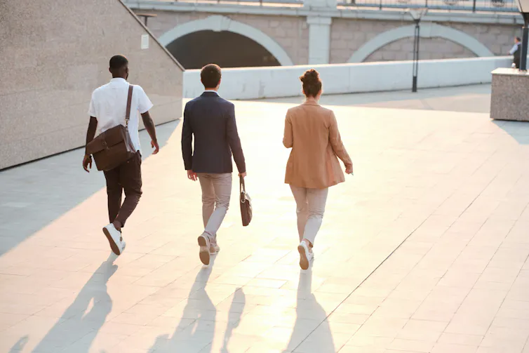 Trois personnes en tenue professionnelle marchant en plein air