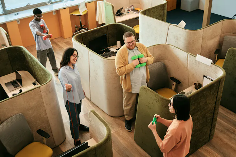 Un espace de bureau avec un employé encourageant ses collègues à faire des étirements et à utiliser des haltères