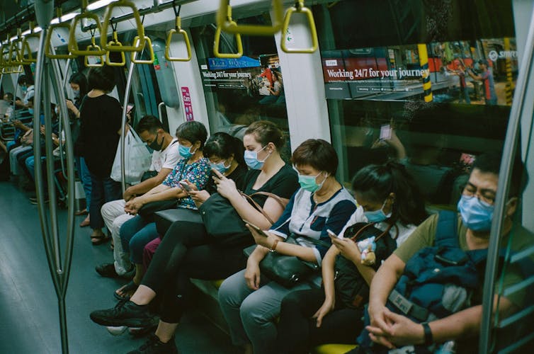 a row of people on public transit holding cellphones