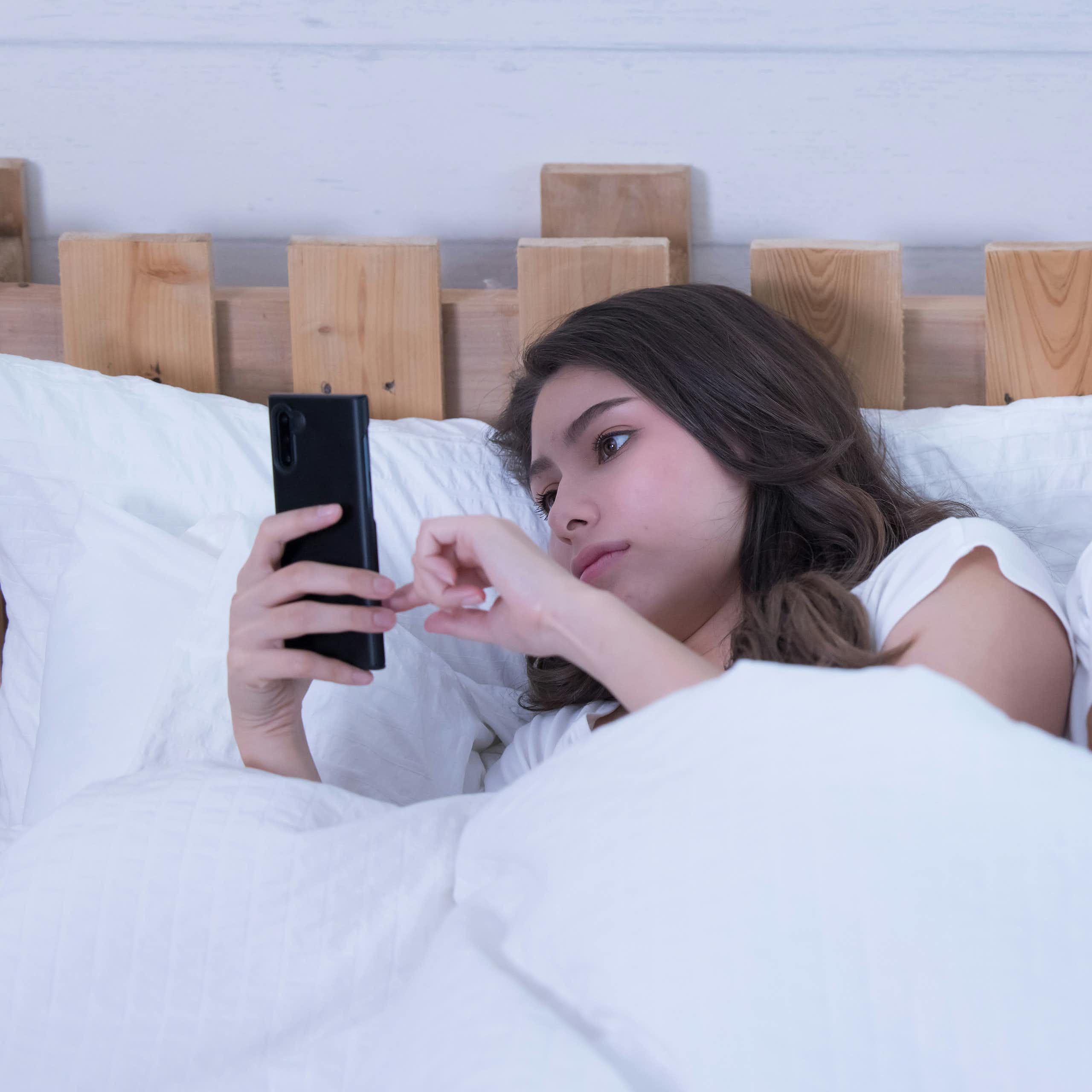 a couple in bed on their phones facing away from each other