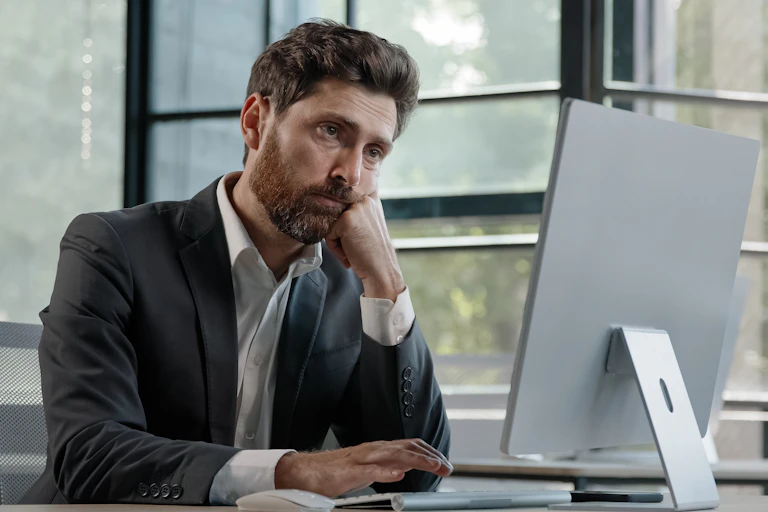 Hombre con aspecto de cansado trabajando con un ordenador
