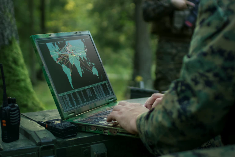 Un soldado maneja un portátil donde aparece un mapa del mundo con objetivos marcados.