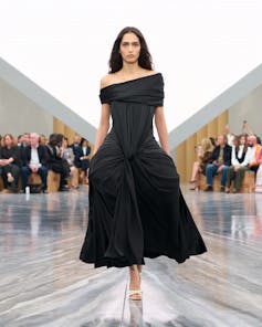 Una mujer desfilando con un vestido negro.