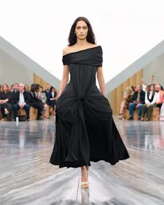 Una mujer desfilando con un vestido negro.